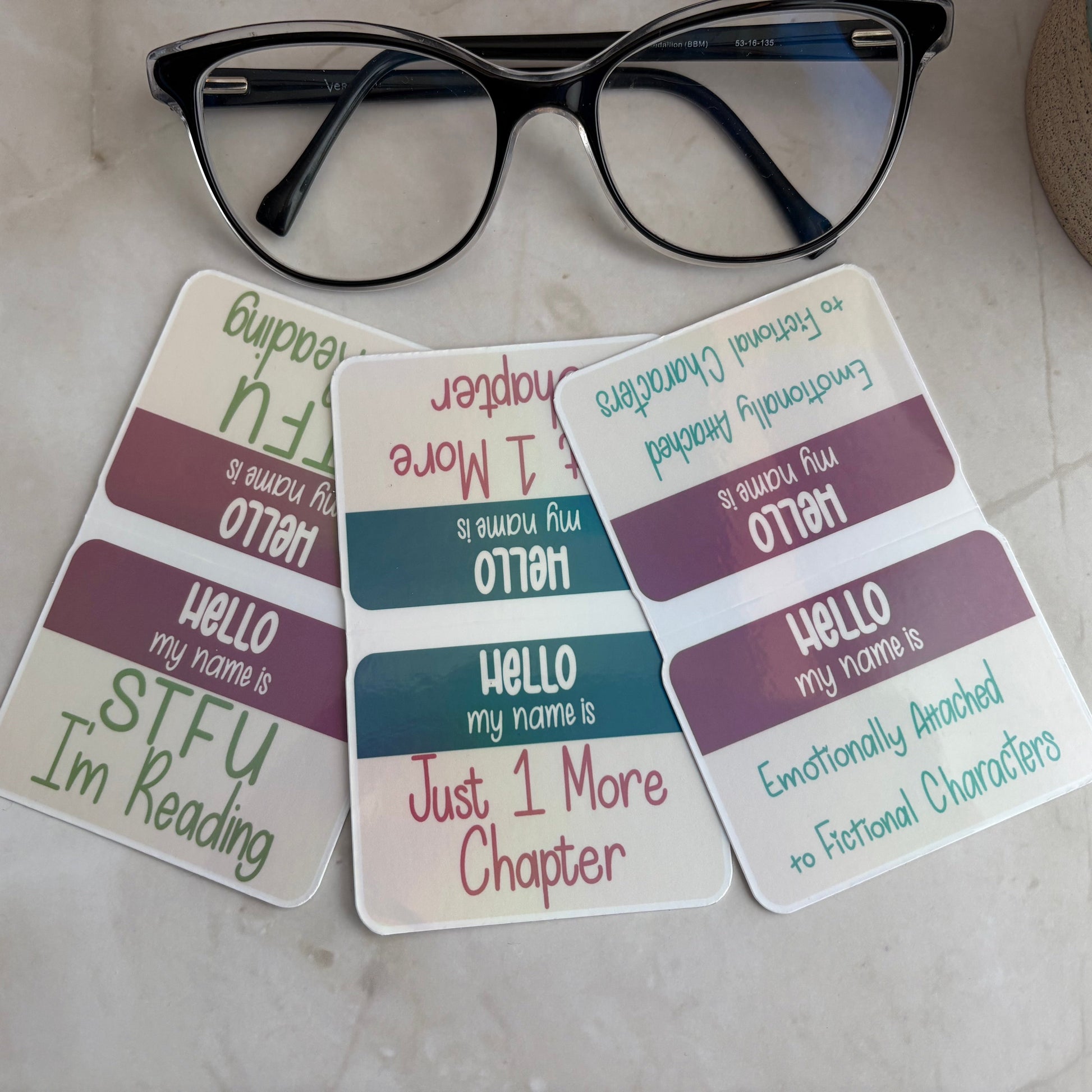 Three name tags with humorous text on a surface with glasses above them