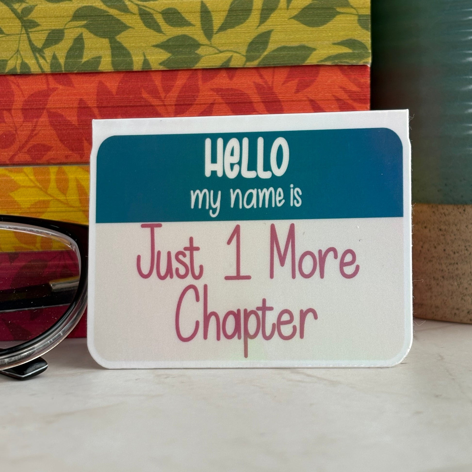 Magnetic bookmark reading 'Hello my name is Just 1 More Chapter' styled with glasses, books, and coffee mug.